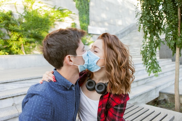 Junges Paar verliebt, Mann und Frau küssen sich in medizinischer Schutzmaske im Gesicht. Konzept der Umweltverschmutzung. Pandemie Coronavirus (Covid-19), Virenschutz