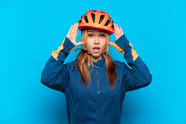 Junges Radfahrermädchen lokalisiert auf blauem Hintergrund mit Überraschungsausdruck
