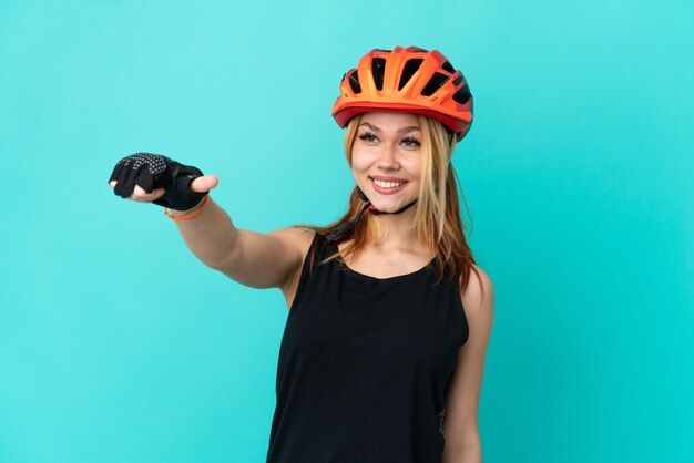 Junges Radfahrermädchen über isoliertem blauem Hintergrund, das eine Geste mit dem Daumen nach oben gibt