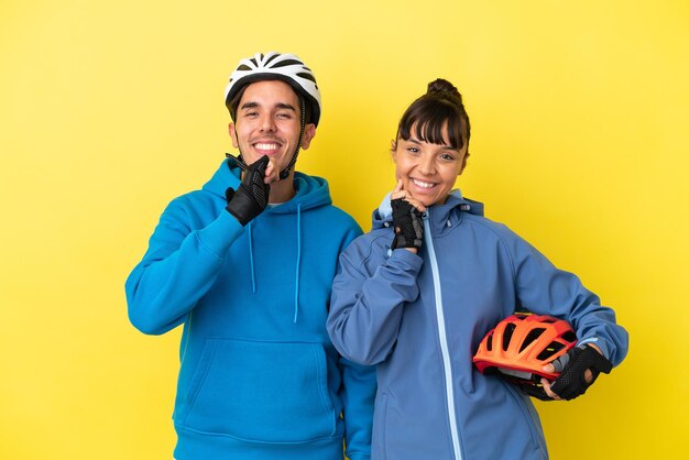 Junges Radfahrerpaar lokalisiert auf gelbem Hintergrund, der mit einem süßen Ausdruck lächelt