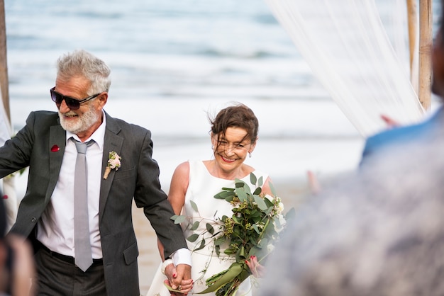 Junges reifes Paar, das am Strand heiraten