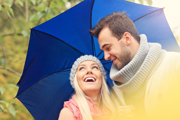 Junges romantisches Paar mit Regenschirm im Park im Herbst