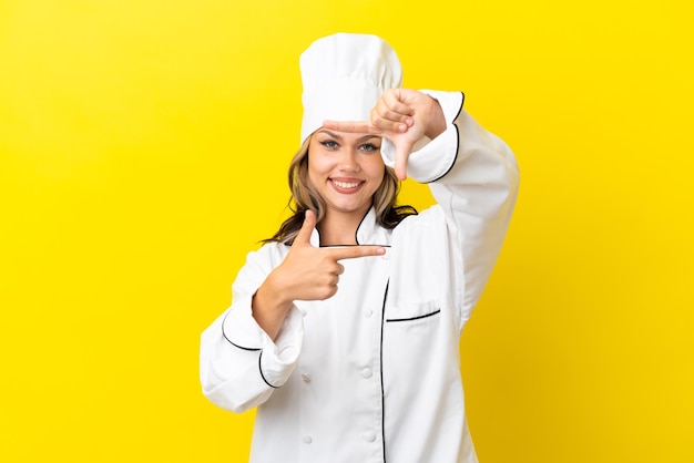 Junges russisches Kochmädchen isoliert auf gelbem Hintergrund mit Fokussierung auf das Framing-Symbol