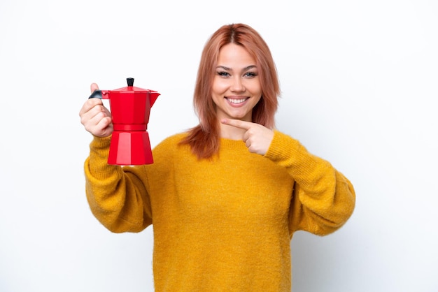 Junges russisches Mädchen, das Kaffeekanne lokalisiert auf weißem Hintergrund hält und es zeigt