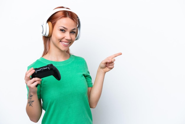 Junges russisches Mädchen, das mit einem Videospiel-Controller spielt, isoliert auf weißem Hintergrund, der mit dem Finger zur Seite zeigt