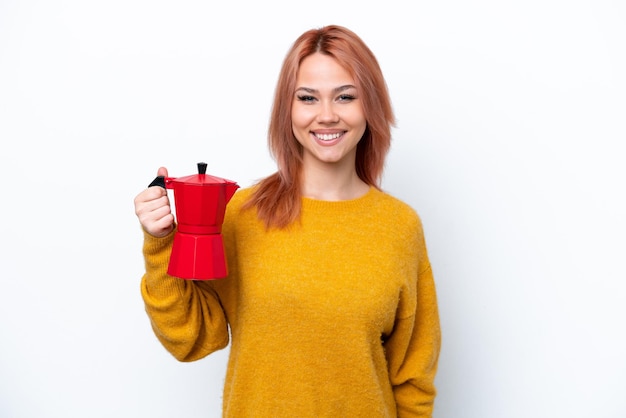 Junges russisches Mädchen mit Kaffeekanne isoliert auf weißem Hintergrund lächelt viel