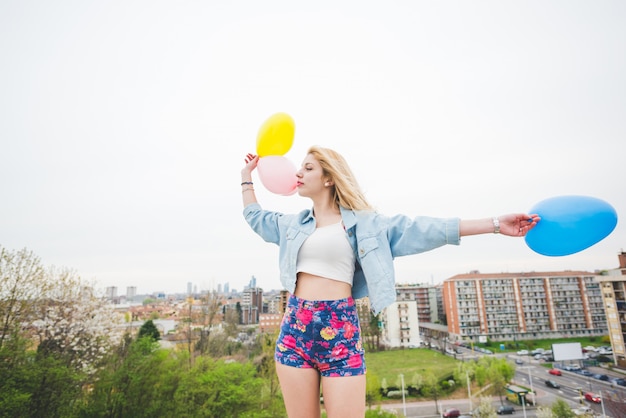 Junges schönes blondes kaukasisches Mädchen, das mit bunten baloons spielt