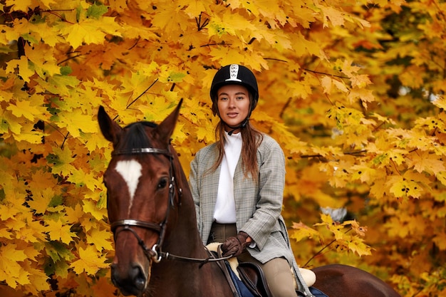 Junges schönes brünettes Mädchen reitet an einem warmen und sonnigen Herbsttag auf einem Pferd Porträt einer hübschen jungen Frau auf dem Pferd mit hohen Stiefeln und Handschuhen