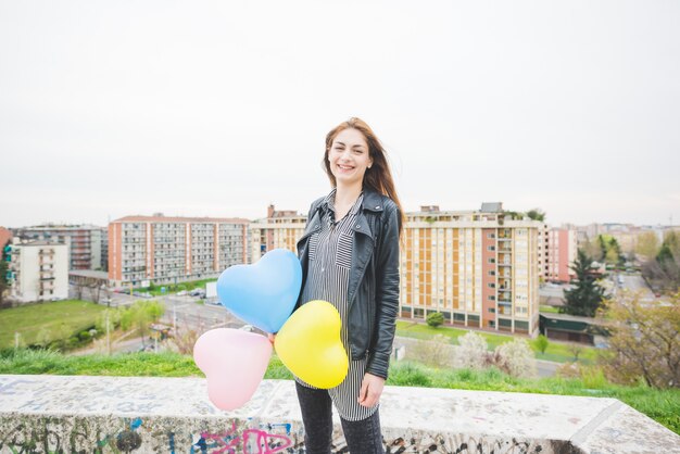 Junges schönes Brunettemädchen, das mit bunten baloons spielt