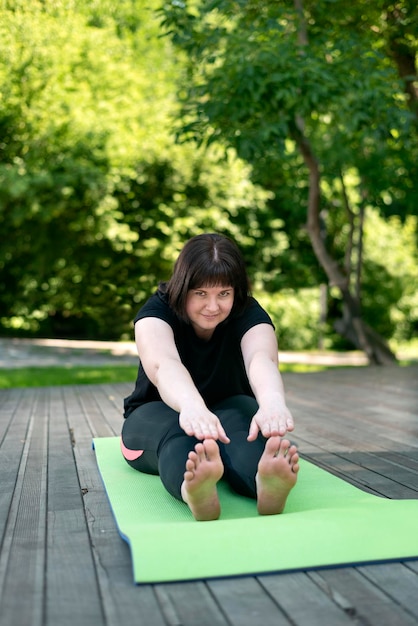 Junges schönes flexibles Mädchen lehnt sich mit den Händen aus einer sitzenden Position nach vorne. Dehnübungen für Anfänger.