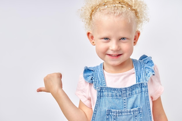 Junges schönes kaukasisches Mädchen mit blonden lockigen Haaren im Jeanskleid über isoliertem weißem Hintergrund ...