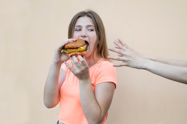 Junges schönes Mädchen, das einen Hamburger isst