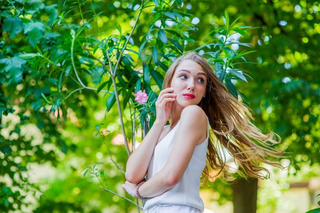 Junges schönes Mädchen, das im Freien aufwirft, modisches weißes Kleid tragend. Sommerstil.