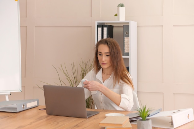 Junges schönes Mädchen im Büro arbeitet am Computer