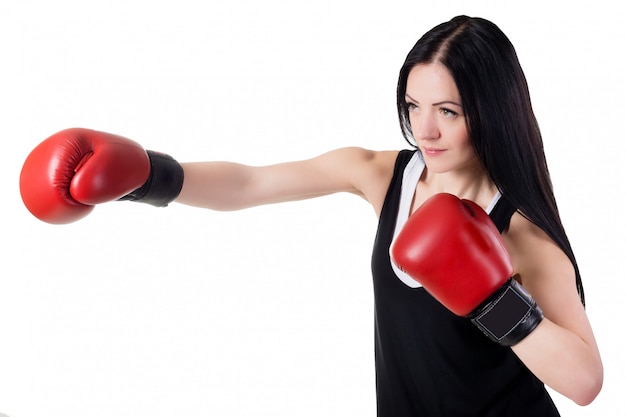 Junges schönes Mädchen in den roten Boxhandschuhen bildet einen Tritt aus