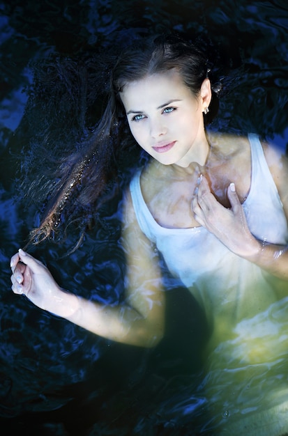 Foto junges schönes mädchen in einem dunklen flusswasser, draufsicht