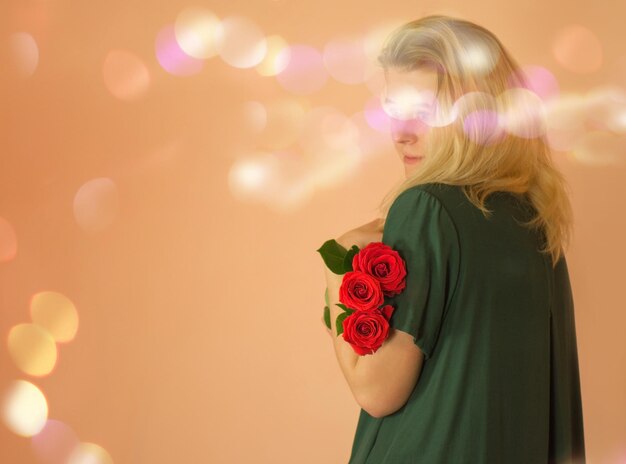 Junges schönes Mädchen in einem strengen, bescheidenen, diskreten, langen grünen Kleid mit roten Rosen