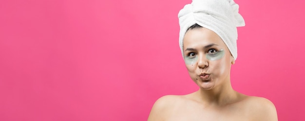 Junges schönes mädchen in einem weißen handtuch auf dem kopf trägt kollagen-gel-pflaster unter den augen maske unter dem augenbehandlungsgesicht