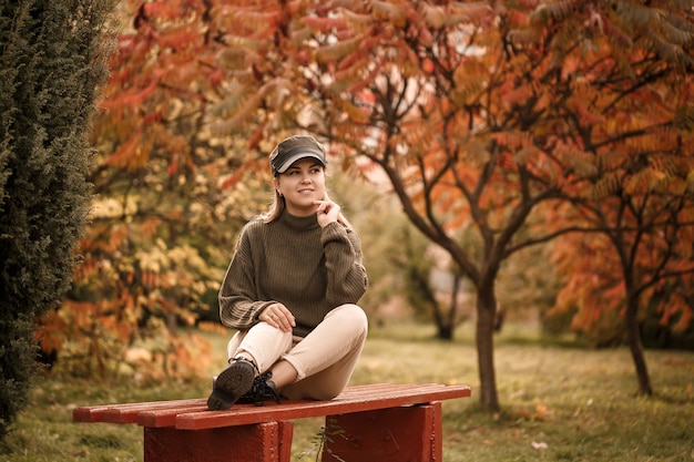 Junges schönes Mädchen in stilvoller Kleidung, grünem Pullover und beige Hose, in einem Herbstpark mit schönen Bäumen