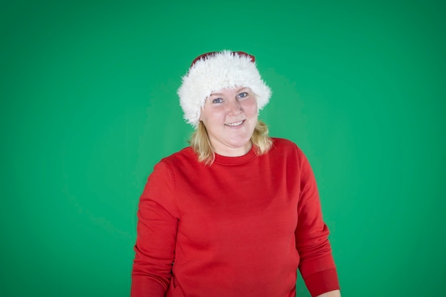 Junges schönes Mädchen in Weihnachtsmütze über isoliertem grünem Hintergrund mit glücklichem Gesicht, das mit einem selbstbewussten Lächeln steht und lächelt.