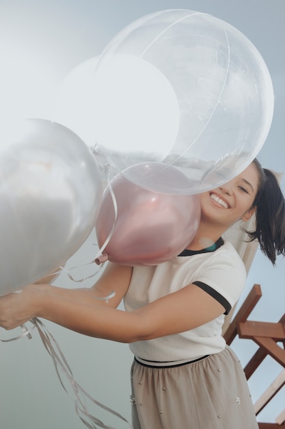 Junges schönes Mädchen lächelnd mit Luftballons feiern