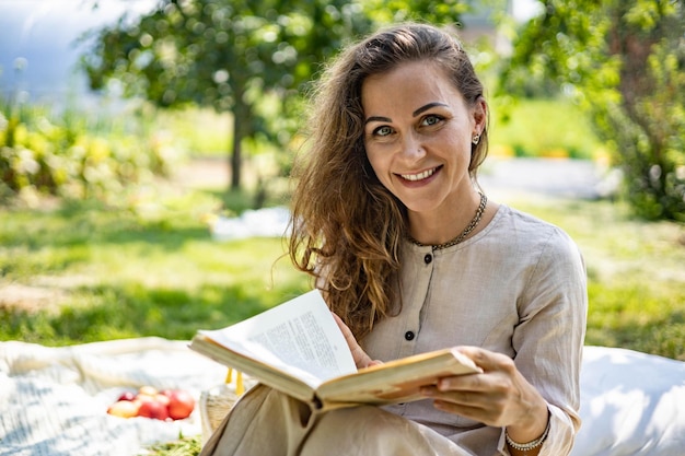 Junges schönes Mädchen liest Papierbuch im Garten