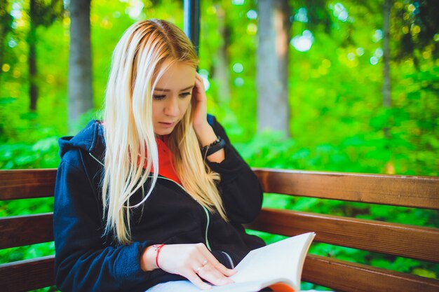 Junges schönes Mädchen mit Buch im Herbstwald