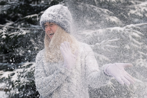 Junges schönes Mädchen mit dem langen weißen Haar spielt Schneebälle