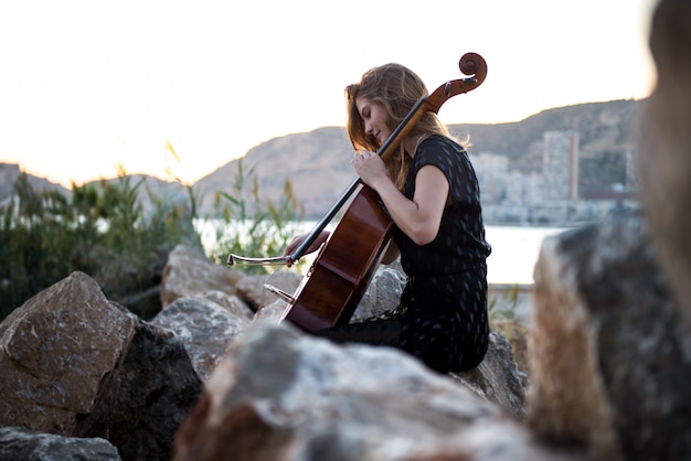 Junges schönes Mädchen mit ihrem Cello auf der Außenseite