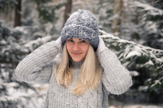 Junges schönes Mädchen mit langen weißen Haaren spielt Schneebälle. Sie hat Spaß, wirft Schnee und freut sich über den Schneefall. Winterspaziergang draußen.