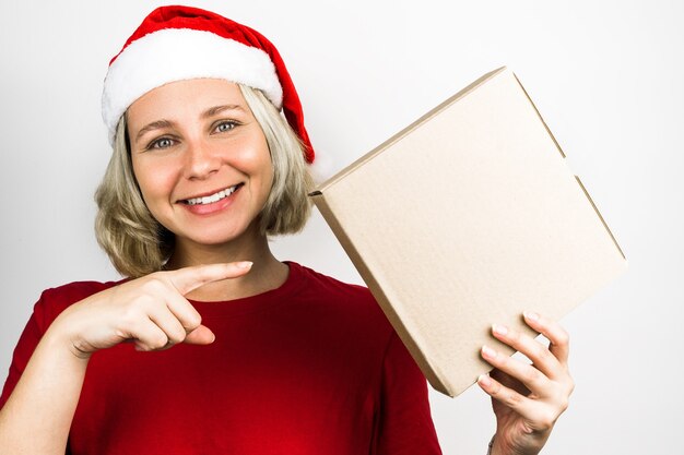 Junges schönes Mädchen mit Weihnachtsmann-Accessoires wie Santa's Cap und rotem Outfit isoliert auf weißem Hintergrund. Foto zu Weihnachten. Brasilianer, Kaukasier, blondes Haar, grüne Augen.