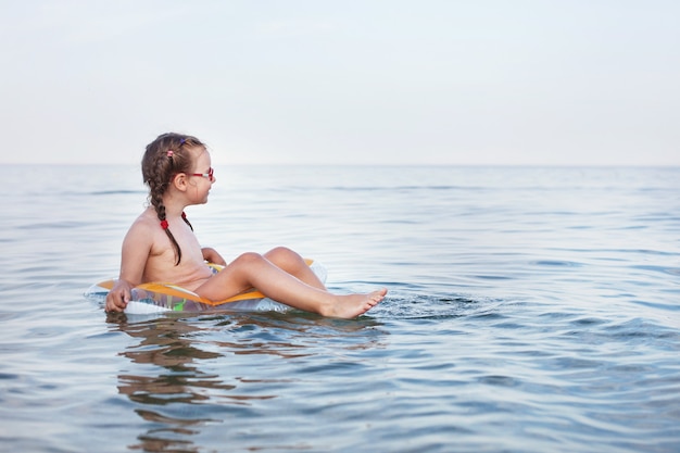 Junges schönes Mädchen schwimmt auf Ð° Gummiring auf dem Meer