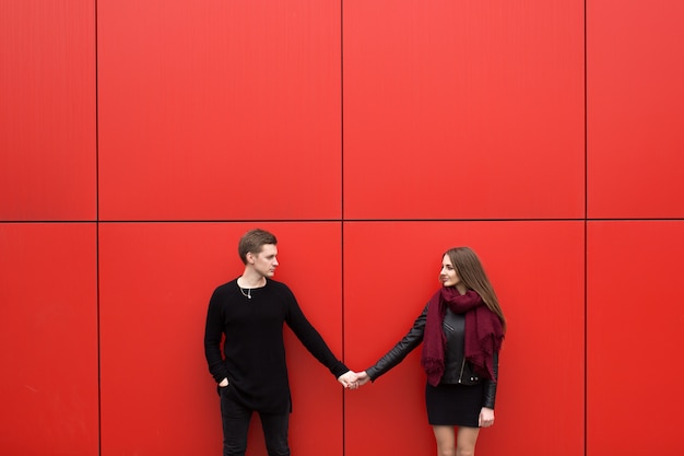 Junges schönes Paar, das an einer roten Wand aufwirft