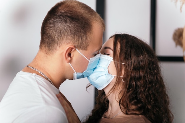 Junges schönes Paar, das sich mit blauer Gesichtsmaske küsst