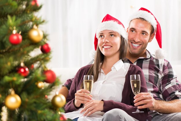 Junges schönes Paar, das Weihnachten oder Neujahr mit einem Glas Champagner feiert.