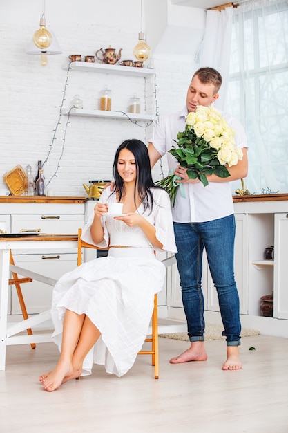 Junges schönes Paar ein Mann gibt einer Frau Blumen für einen Urlaub zu Hause