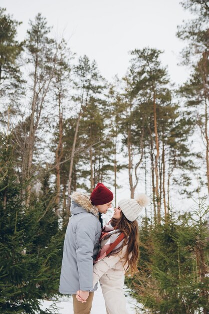 Junges schönes Paar umarmt in einem Winter-Nadelwald