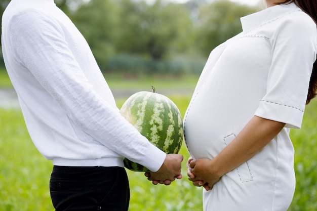 Junges schönes schwangeres Paar mit Wassermelone in den Händen