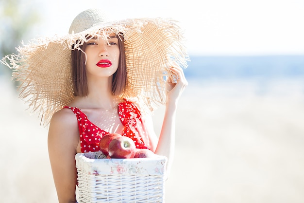 Junges Schönheitsporträt draußen auf saftigem Sommer oder Herbst Frau auf Abfallzeit. Dame auf der Natur, die rotes stilvolles Kleid trägt.