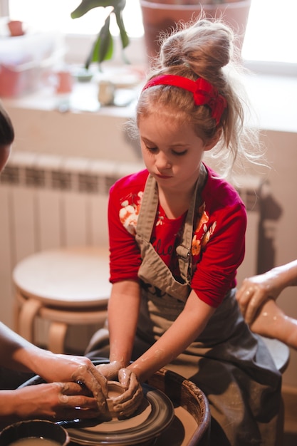 Junges siebenjähriges Mädchen in der Töpferei, das eine Schüssel aus Ton herstellt. Töpferwerkstatt für Kinder.