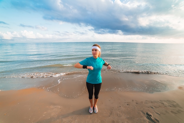 Junges sportliches Mädchen, das Training auf Strand am Sonnenaufgang am Morgen tut