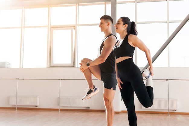Junges sportliches Paar beim Training wärmt sich morgens im Fitnessstudio auf, Mann, Trainer und Frau