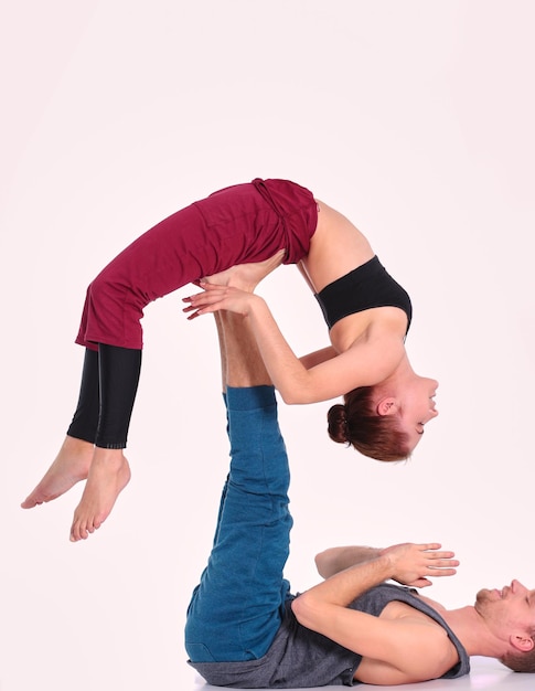 Junges sportliches Paar, das Acroyoga praktiziert, das paarweise balanciert