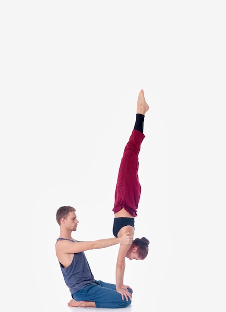 Junges sportliches Paar, das Acroyoga praktiziert, das paarweise balanciert