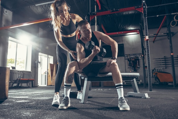 Junges sportliches Paar, das zusammen im Fitnessstudio trainiert