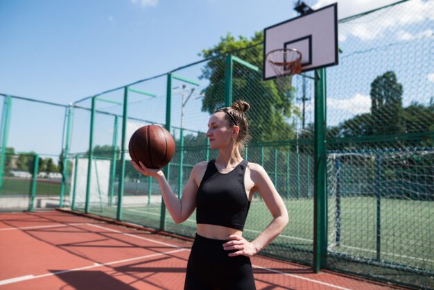 Junges Sportmädchen mit einem Basketball auf dem Basketballplatz im Freien aktives Wochenende