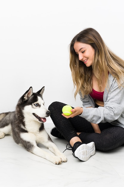 Junges Sportmädchen mit ihrem Hund, der auf dem Boden sitzt