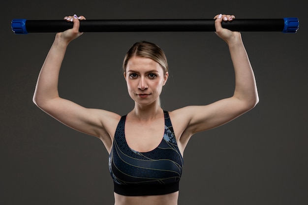 Junges Sportmädchen mit langen blonden Haaren, die mit Schwanz bedeckt sind, schönes Aussehen, Sportkörper, oben und an den Beinen, hält Sportausrüstung in den Händen