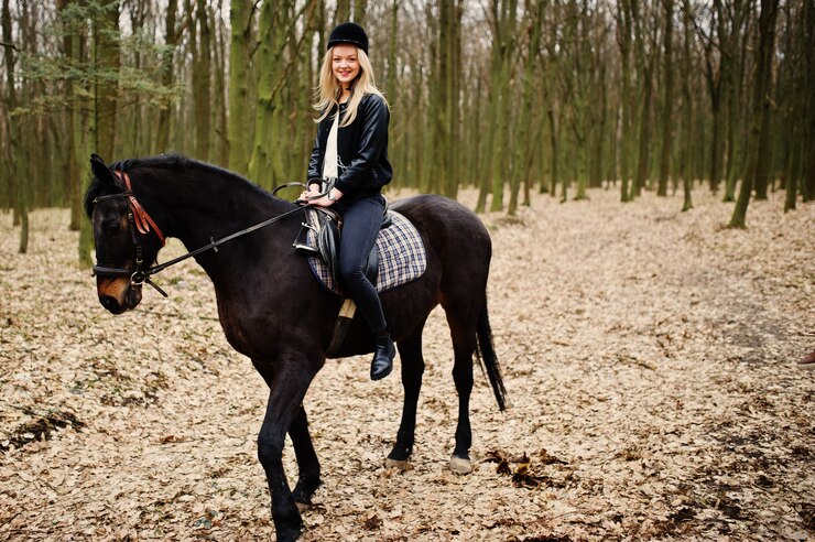 Junges stilvolles Blondinereiten auf Pferd am Herbstwald