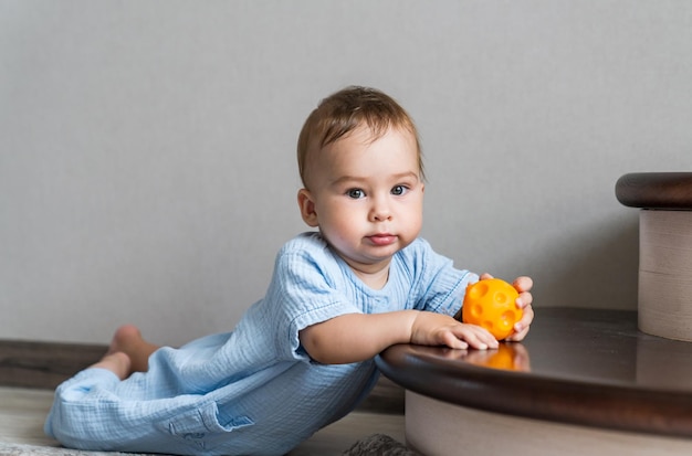 Junges süßes Kind mit Ball auf dem Boden Entzückendes Baby mit buntem Spielzeug